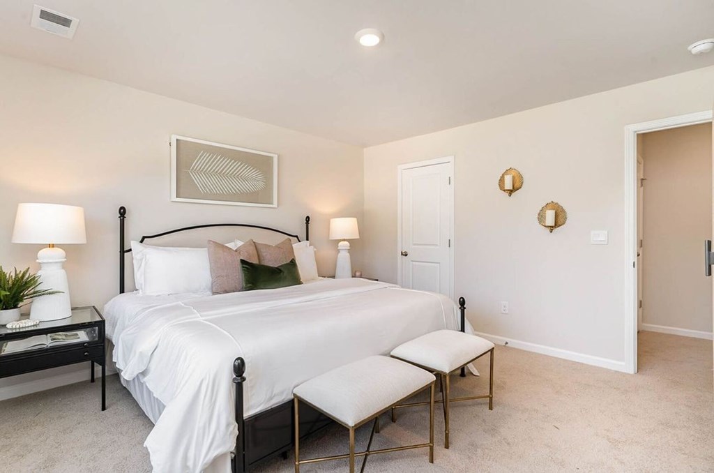 A bedroom with a bed, nightstand, and chair.