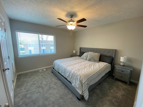 A bedroom with a bed, nightstand, and window.