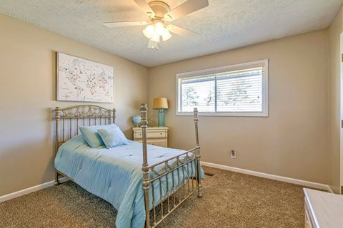 A bedroom with a bed, nightstand, and window.