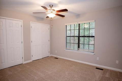 A room with a ceiling fan and a window with blinds.