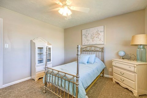 A bedroom with a bed, dresser, and ceiling fan.