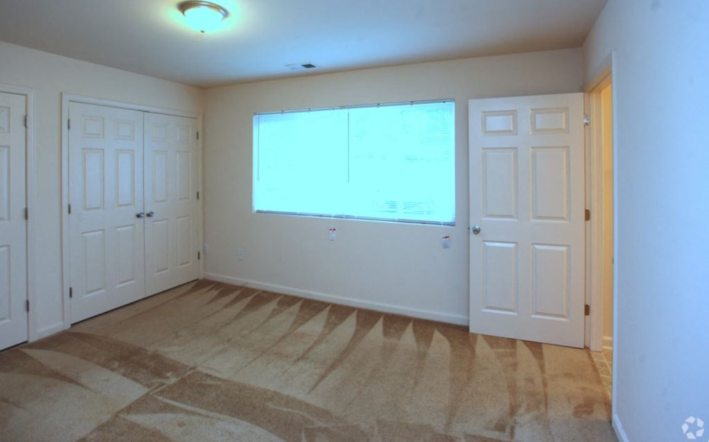 an empty living room with two doors and a window