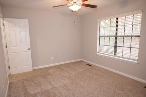 A room with a ceiling fan and a window with blinds.