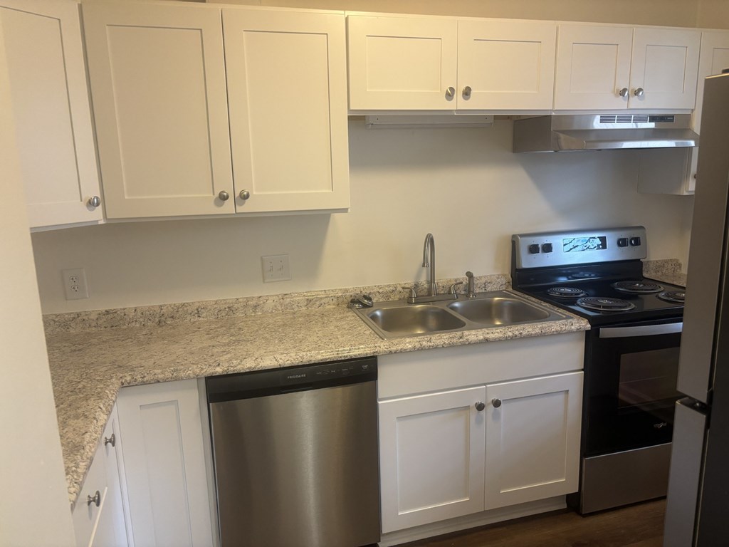 A kitchen with white cabinets and a granite countertop.