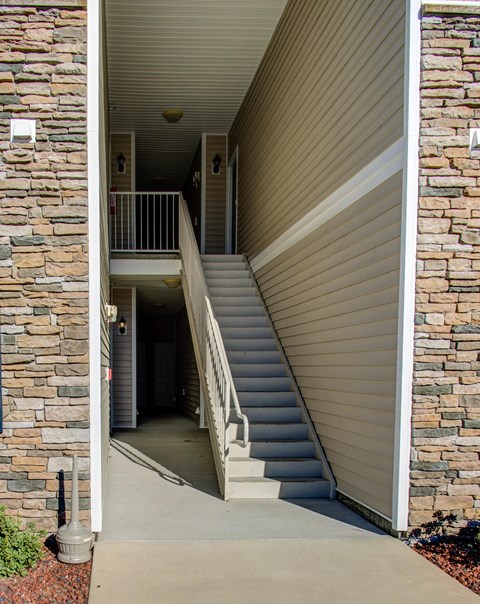 A staircase with a metal railing leads to a doorway.