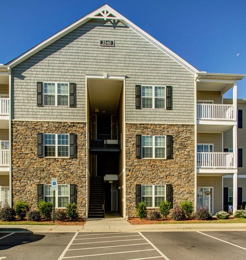 The front of apartment building number 3340 with a parking lot in front.