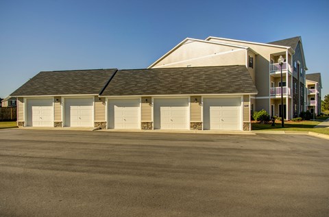 A large building with a grey roof and white walls with a parking lot in front.