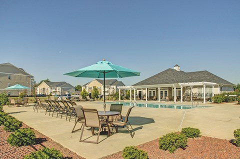 A patio with chairs and umbrellas overlooking a pool.