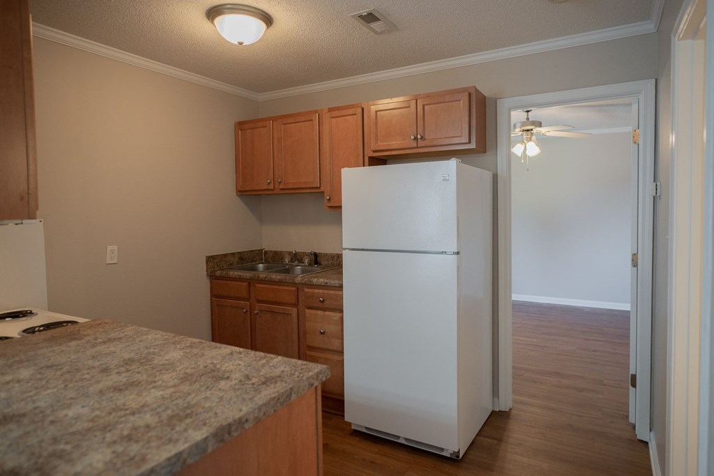 A kitchen with a white refrigerator and wooden cabinets.