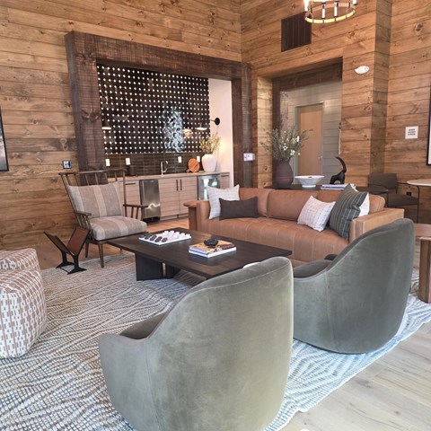 A living room with a brown couch and grey chairs.