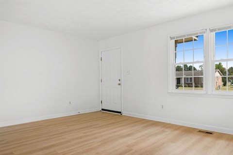 A room with a white door and a window with a view of a building outside.