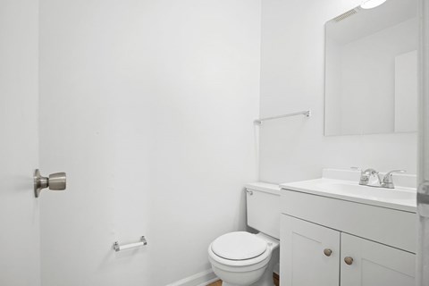 A white bathroom with a toilet, sink, and mirror.