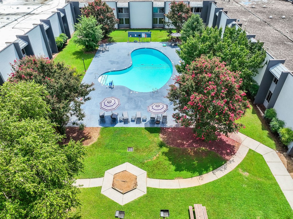 A swimming pool surrounded by trees and a building in the background.