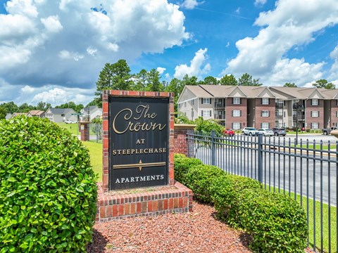 A sign for The Crest at Steeplechase Apartments is in front of a building.