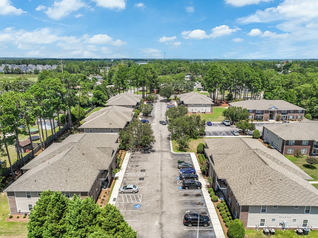 A sunny day at the apartment complex with cars parked in the parking lot.