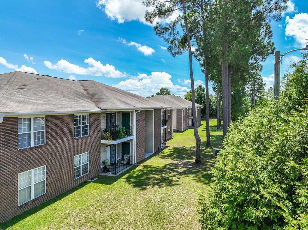 A row of houses with green lawns and trees.
