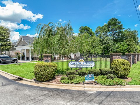A street view of Church Street with a sign, a car, and a house.