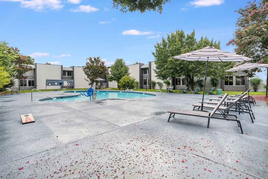 A pool area with a table and chairs and a building in the background.