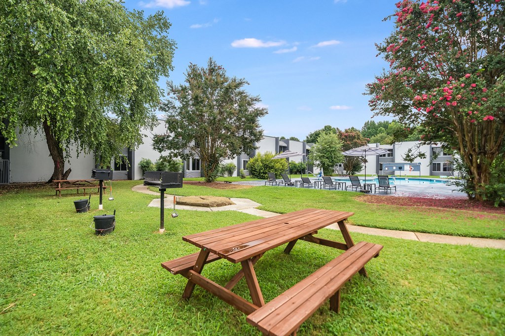 A picnic table and bench are in the foreground of a grassy area.