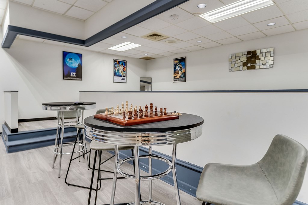 A chess board with chess pieces on it sits on a table in a room.