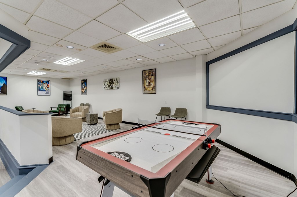 A shiny air hockey table is in the middle of a room with a white wall and a white ceiling.