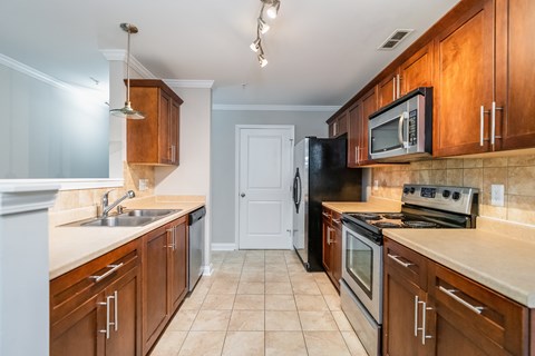 A kitchen with brown cabinets and a black refrigerator.
