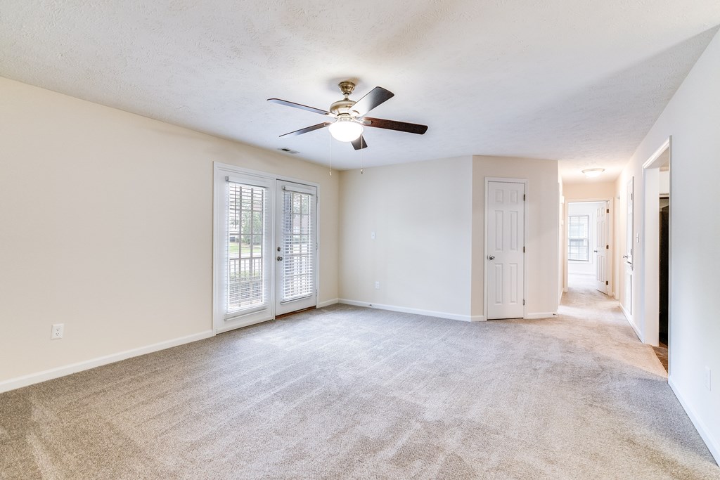 A room with a ceiling fan and carpeted floor.