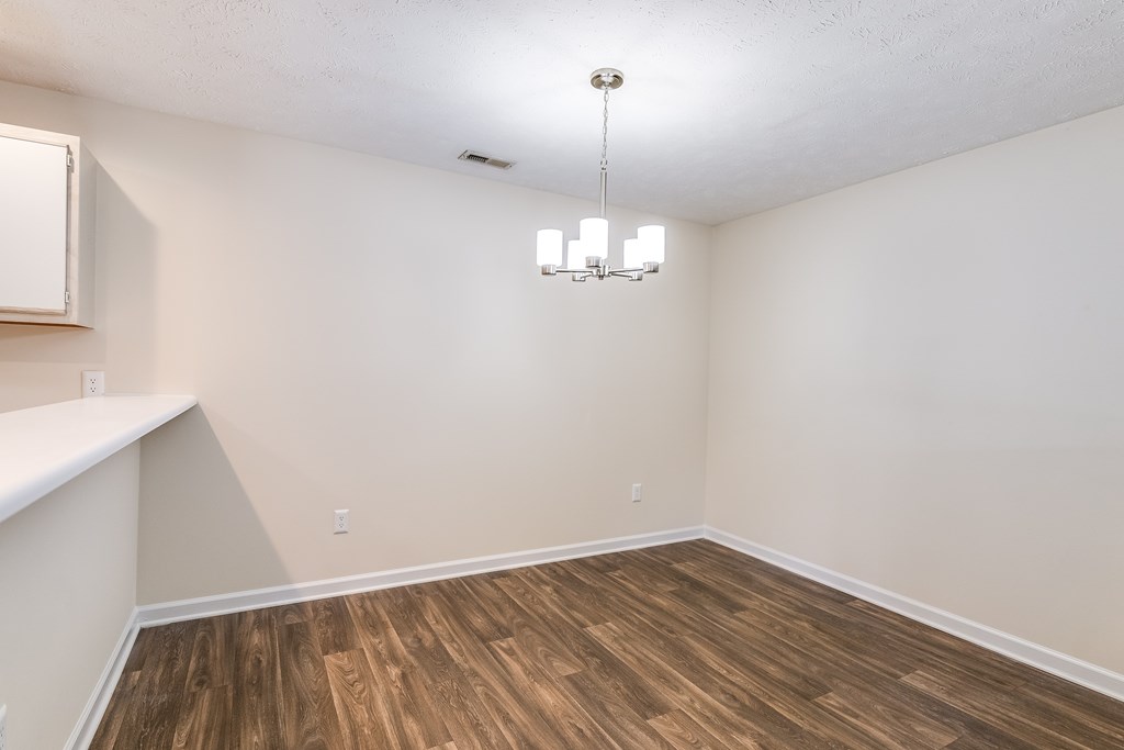 A room with wooden flooring and a chandelier hanging from the ceiling.