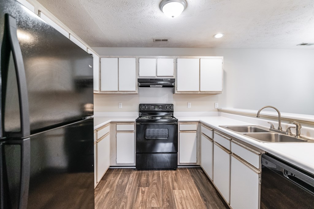 A black stove and oven in a kitchen with white cabinets.