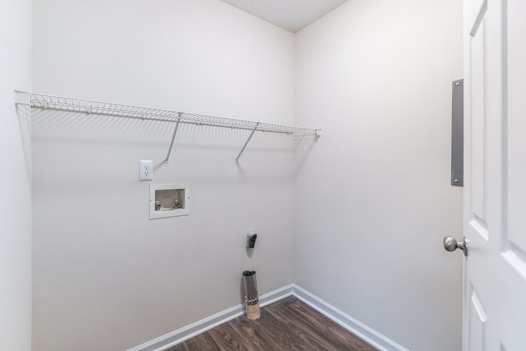 A white wall with a white door and a white shelf.