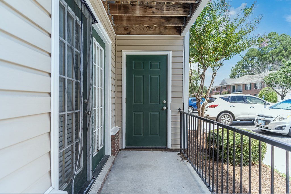 A green door is on the right side of a white house.