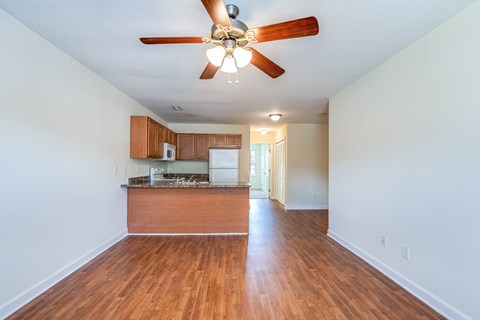 A room with a ceiling fan and wooden floors.
