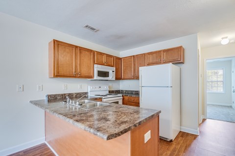 A kitchen with a granite countertop and wooden cabinets.