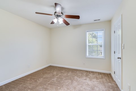 A room with a ceiling fan and a window.