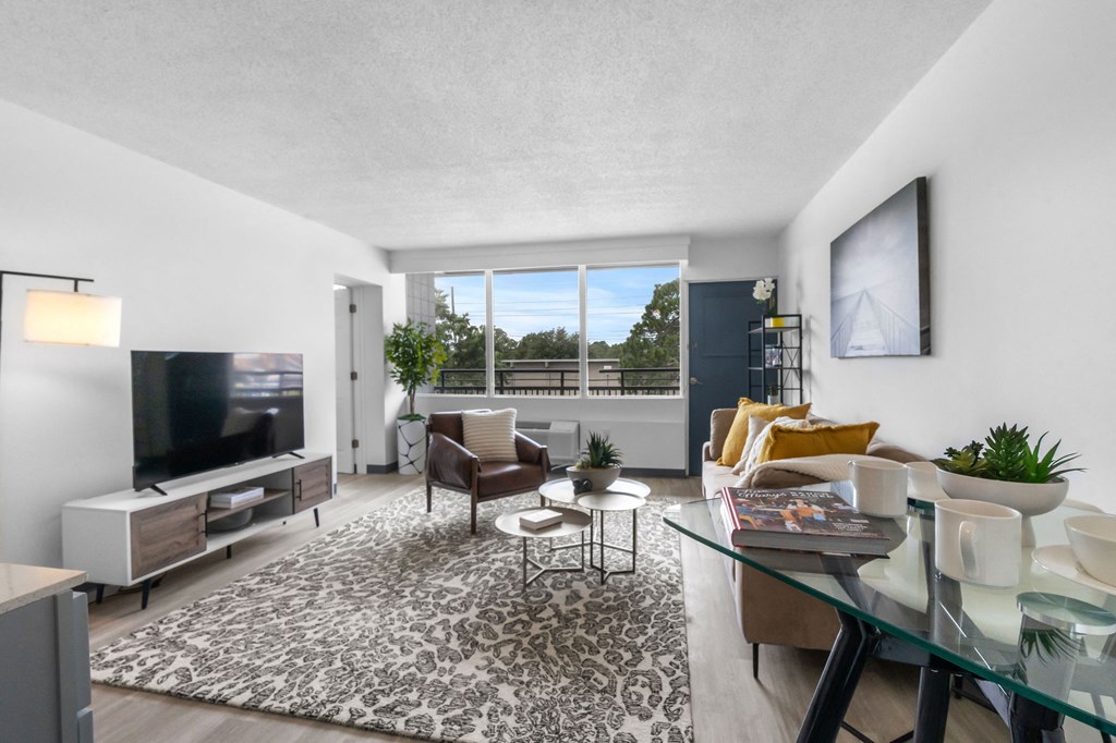 A modern living room with a flat screen TV and a glass coffee table.