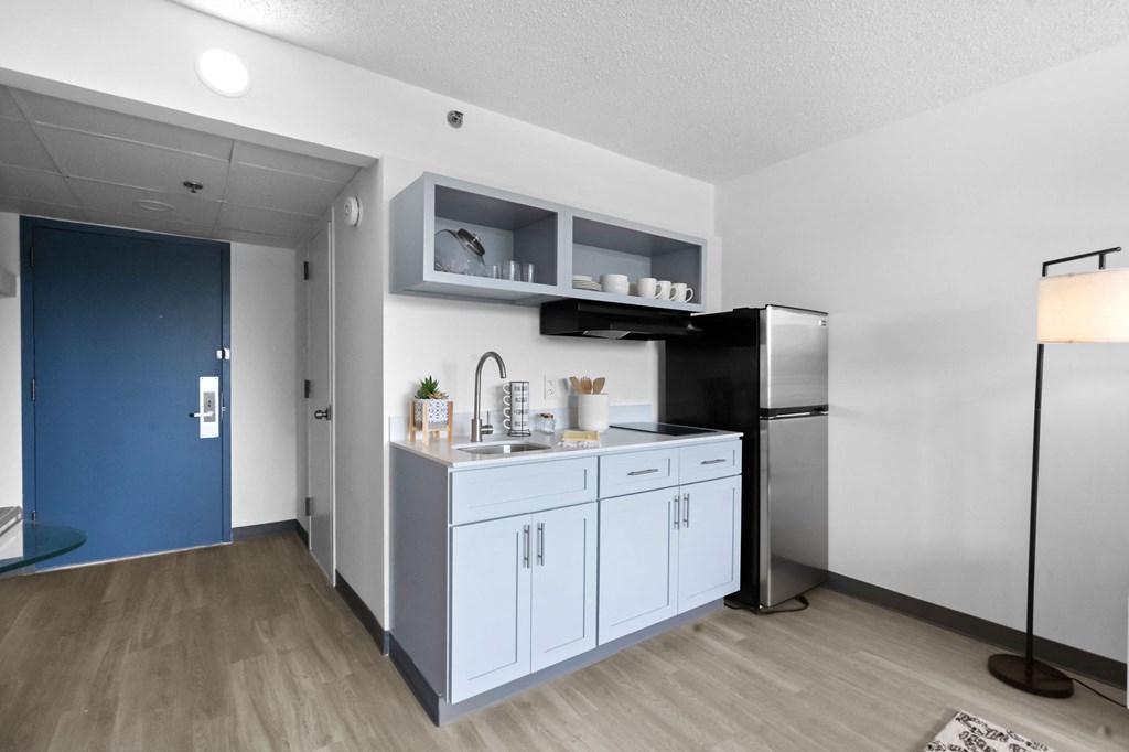 A kitchen with a refrigerator, sink, and cabinets.
