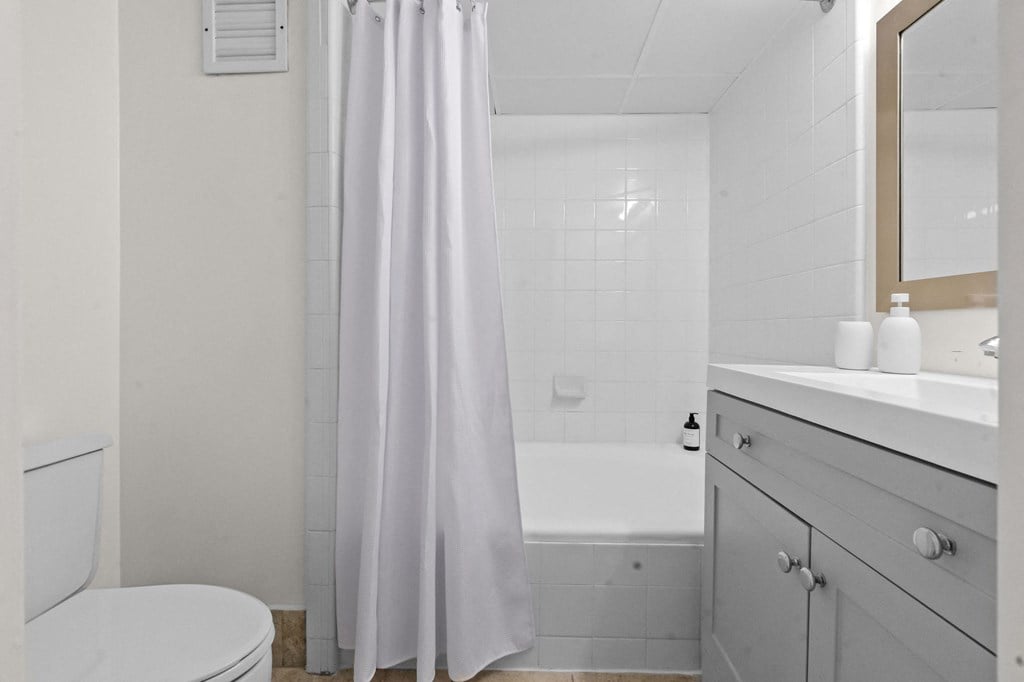 A white bathroom with a toilet, sink, and shower.