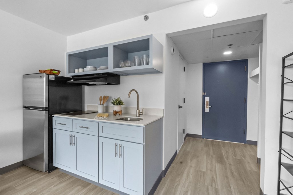 A kitchen with a sink, refrigerator, and cabinets.