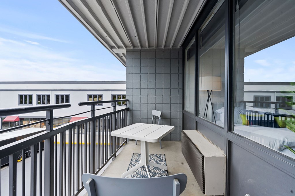 A balcony with a table and chairs overlooking a cityscape.