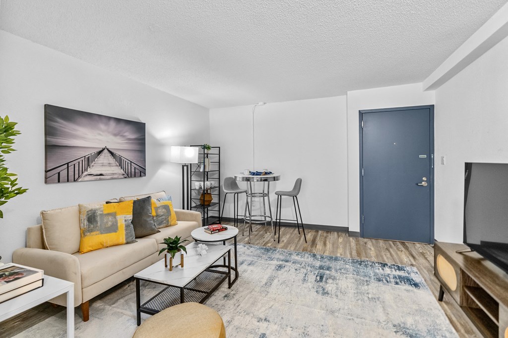 A living room with a couch, a coffee table, a rug, and a painting on the wall.