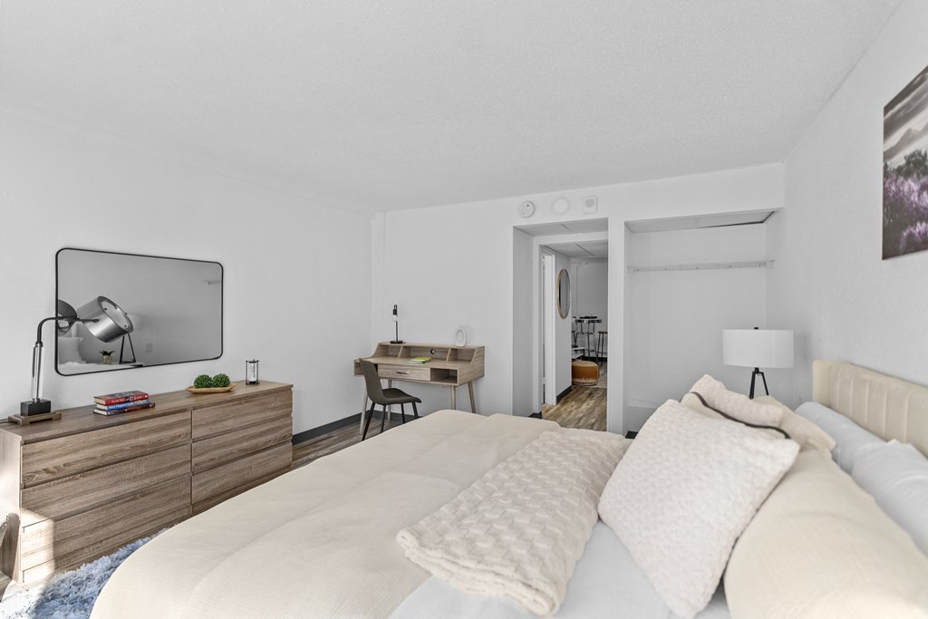 A bedroom with a large bed and a desk with a chair.