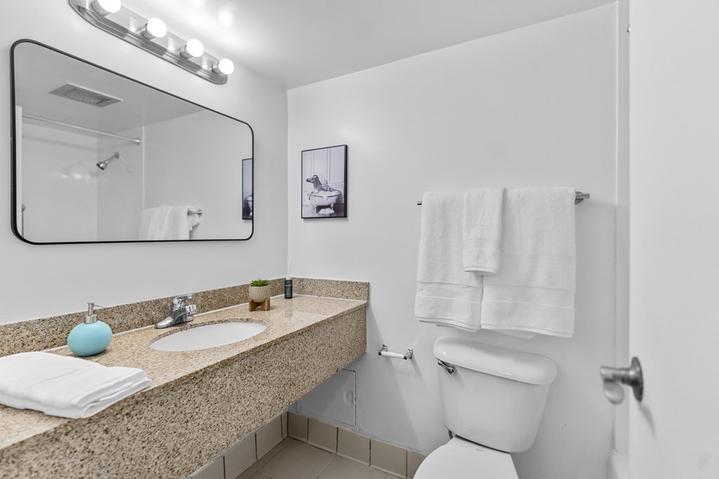 A bathroom with a toilet, sink, and mirror.