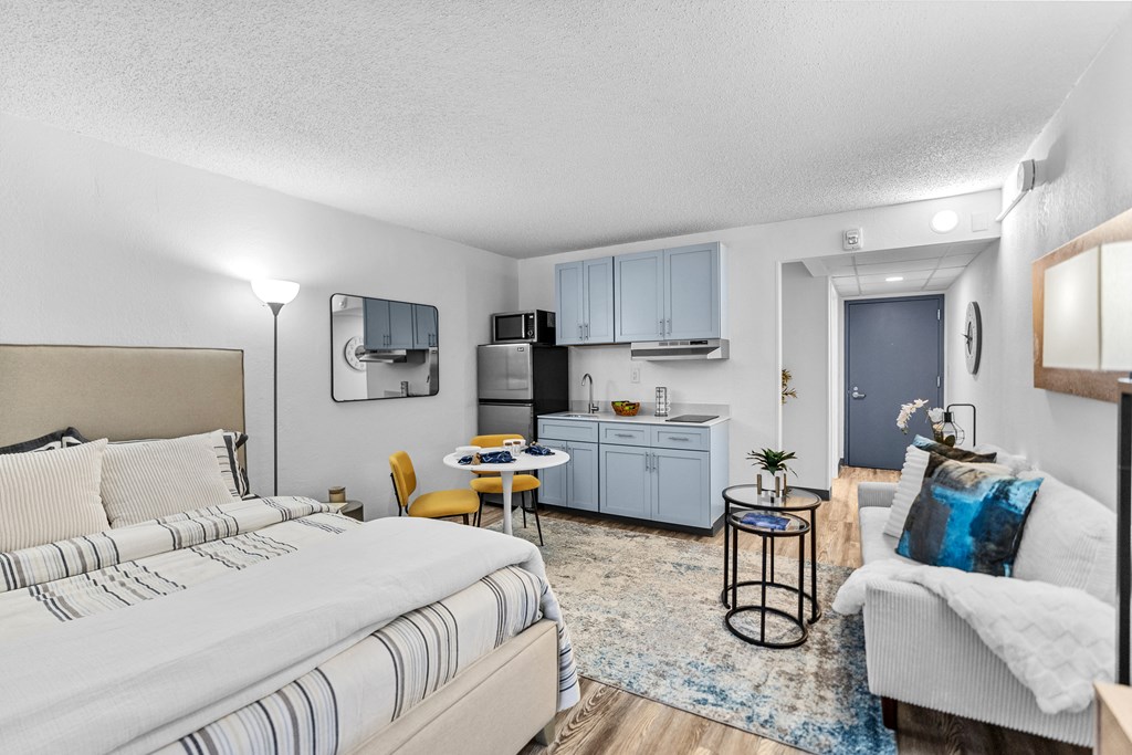 A bedroom with a bed, a couch, and a small kitchenette.