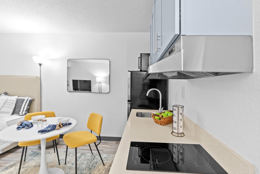 A modern kitchen with a white table and yellow chairs.