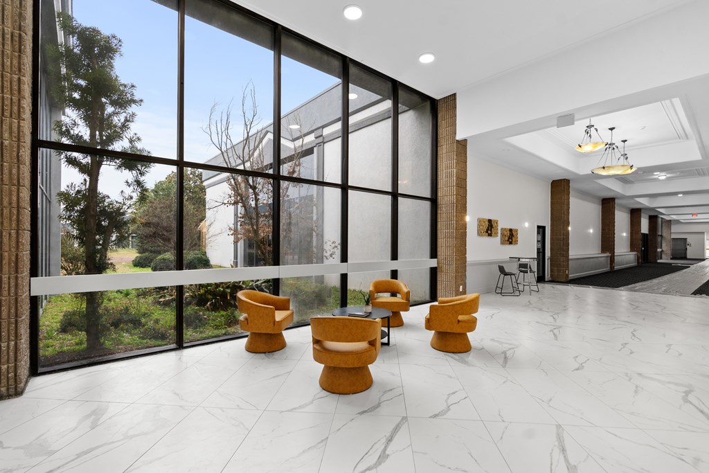 A spacious lobby with yellow chairs and a marble floor.