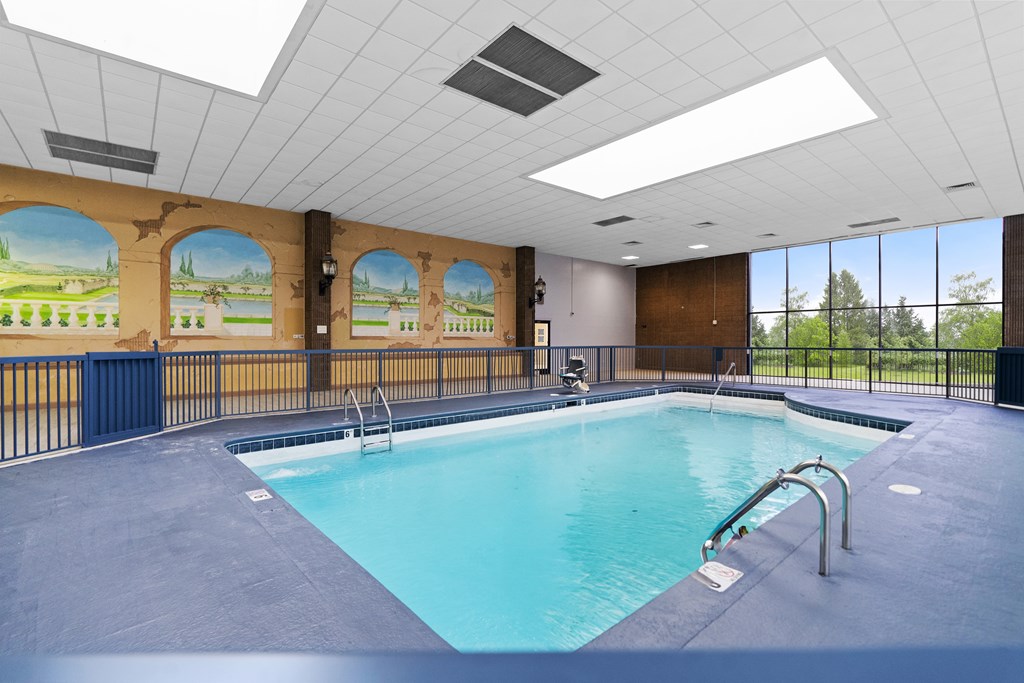 A large indoor swimming pool with a view of the outdoors through the windows.