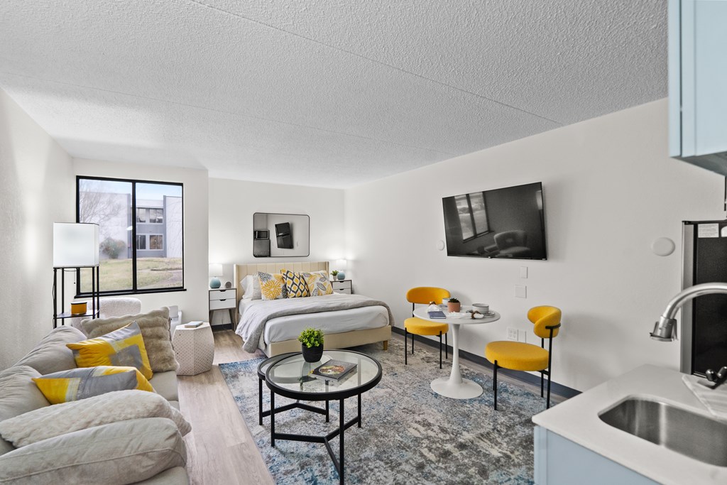 A modern living room with a yellow chair and a white sofa.