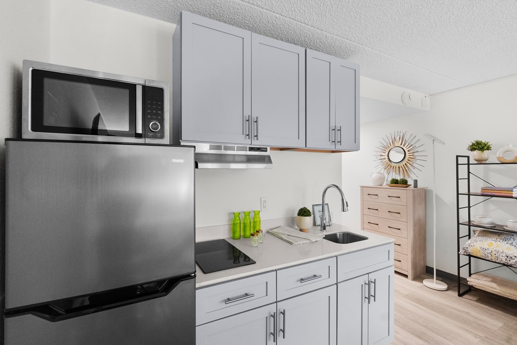 A modern kitchen with a stainless steel refrigerator and white cabinets.