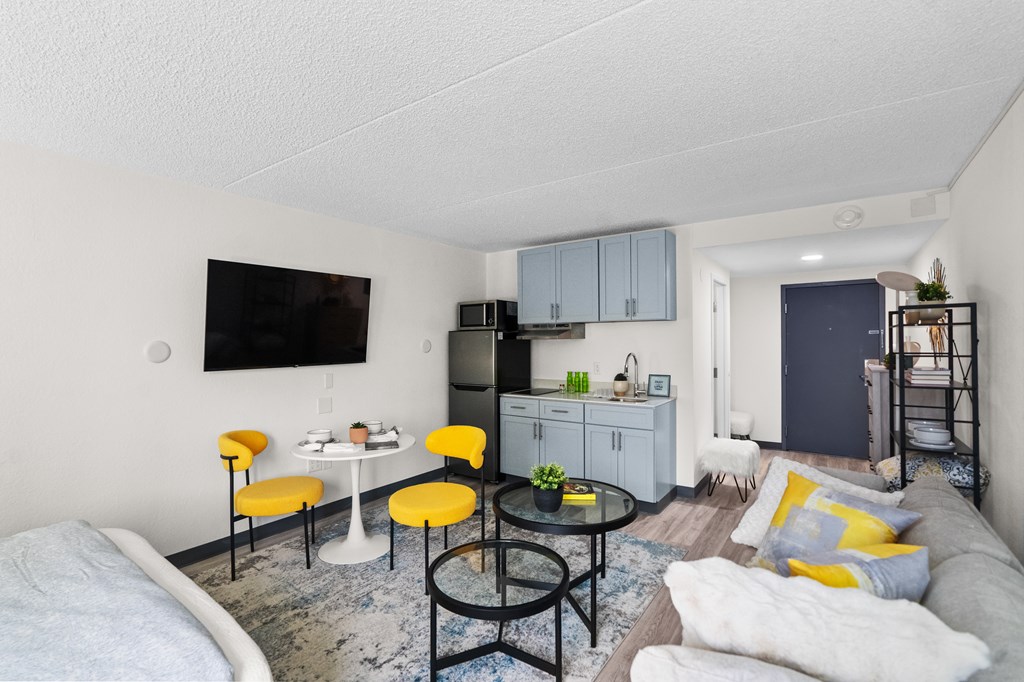 A living room with a grey couch, yellow chairs, and a black table.