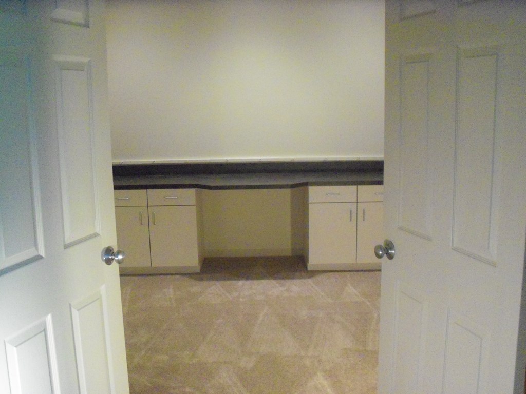 A white door is open to a room with a bench and cabinets.